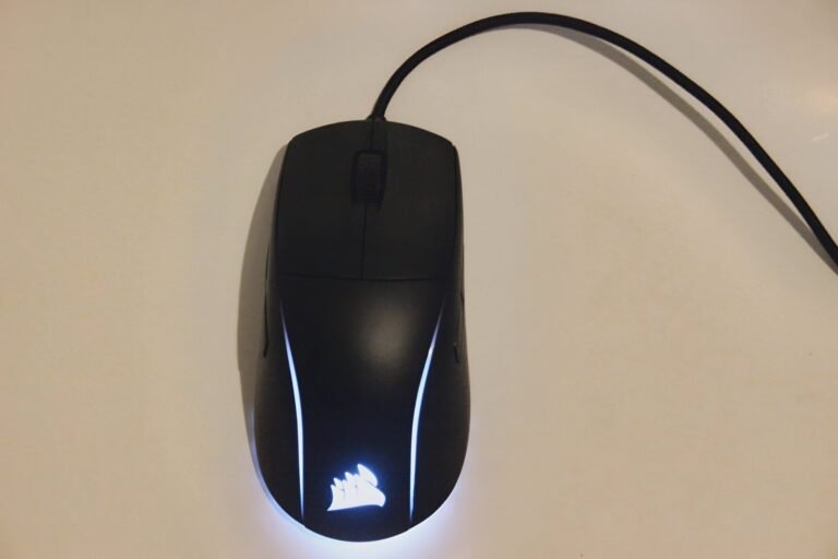 Corsair M75 wired RGB gaming mouse with white LED logo and streamlined black design.