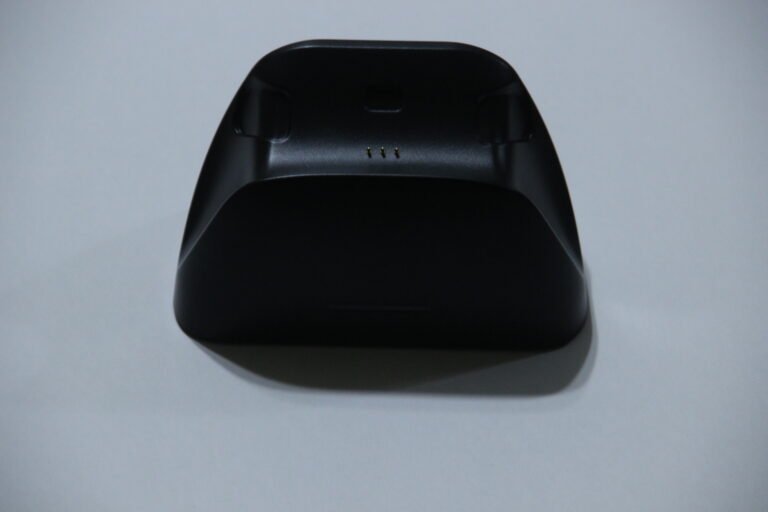 Back view of a black charging dock/cradle with three small gold contact pins in the center