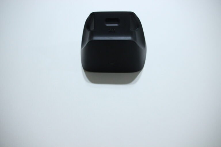 Black wireless device charging dock on a light surface, viewed from above, no device resting on it.