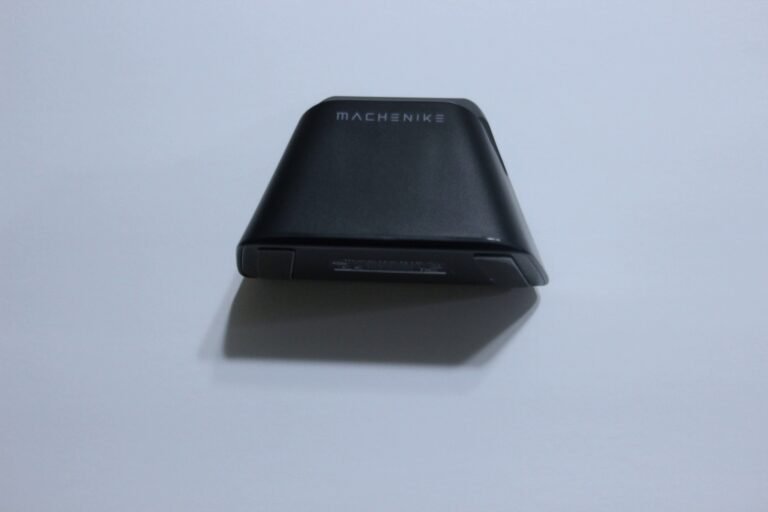 Wedge-shaped black gadget with 'MACHENIKE' logo on its top, resting on a white surface.