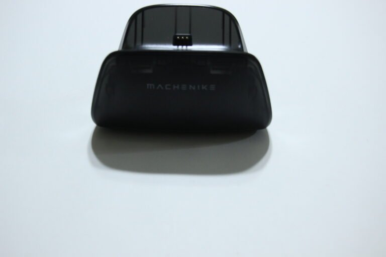 Black MACHENIKE charging dock seen from front with a small connector at the top of the cradle, resting on a white surface