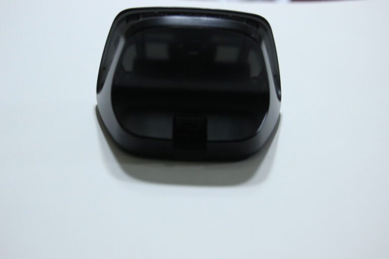 Front view of a black VR headset resting on a white surface, showing its curved visor and compact frame.