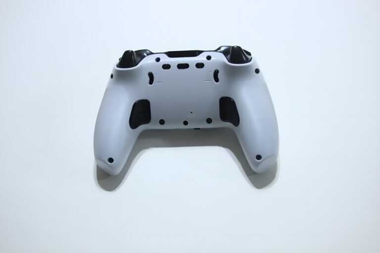 Back view of a white game controller with black grips and exposed buttons/triggers on a light background