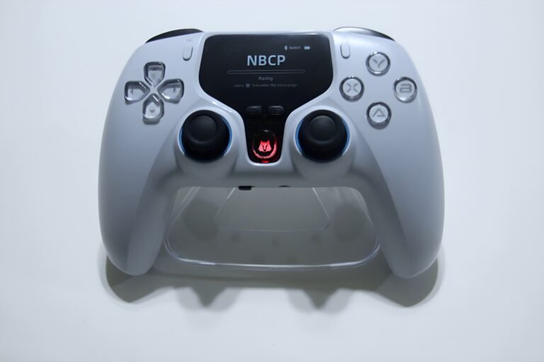Close-up of a white game controller on a light surface, showing two analog sticks, D-pad, and colored action buttons on the right.