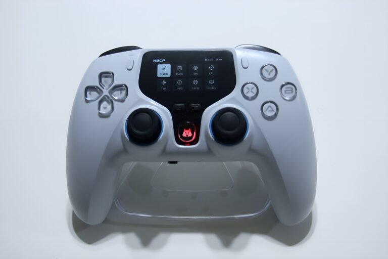 Front view of a white game controller with a small central display and blue-thumbstick joysticks