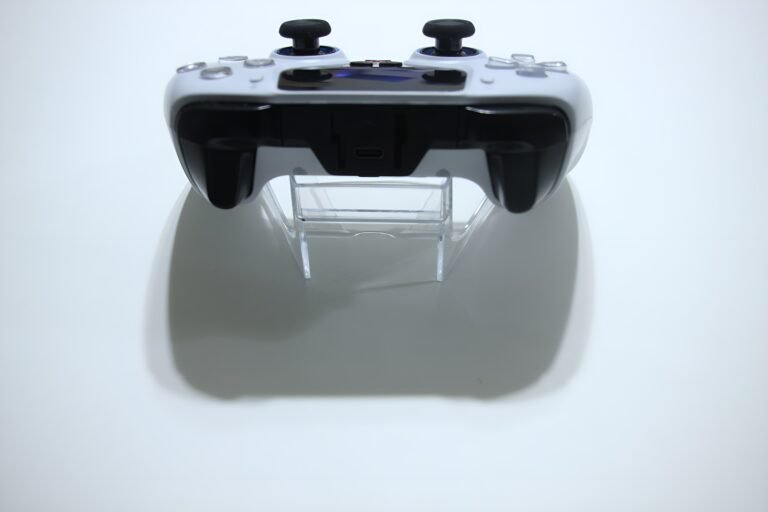 Front view of a white video game controller with two black analog sticks on a clear stand.