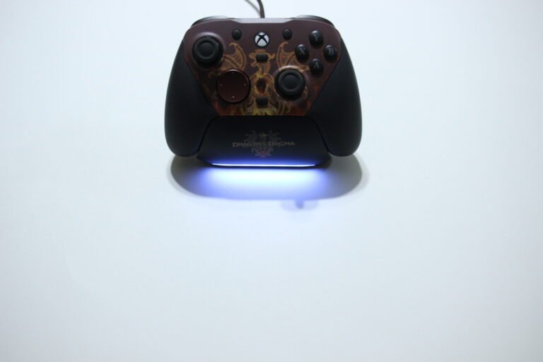 Dragon's Dogma themed Xbox controller resting on its charging stand with a blue LED glow underneath.