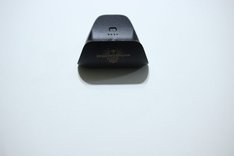 Black Dragon's Dogma charging dock on a white surface with five gold contact pins.