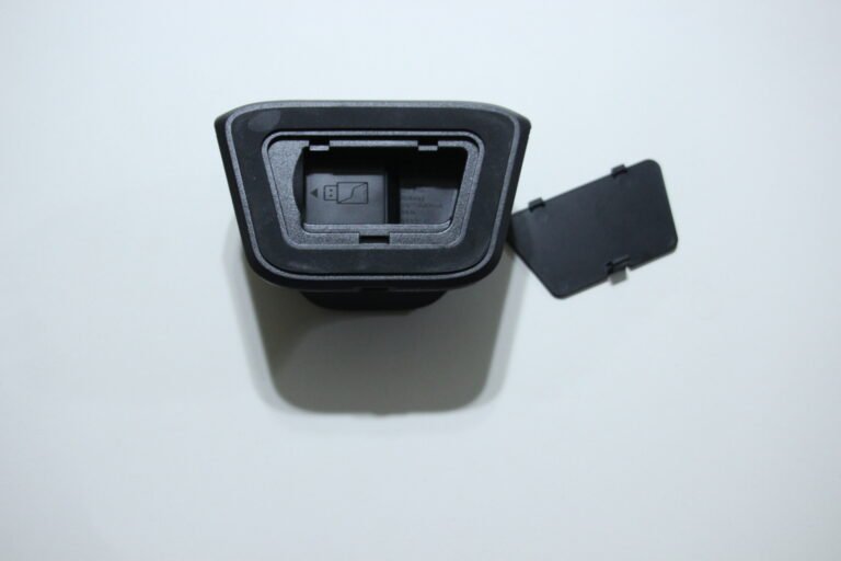 Close-up of a black plastic camera accessory with an open rectangular slot and a hinged side cover.