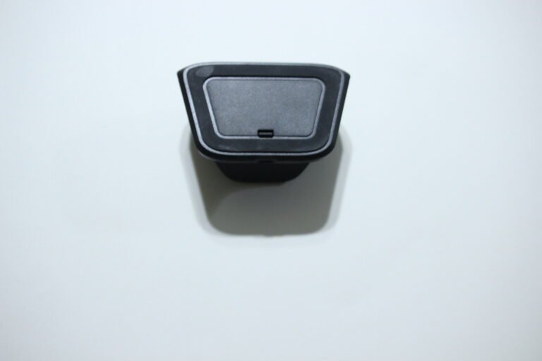 Top view of a black plastic device with a gray inner panel and small notch, resting on a white surface.